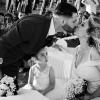 Un bacio tra gli sposi e lo sguardo curioso della bambina accanto a loro: famiglia e matrimonio nello stesso istante.