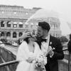 Gli sposi si stringono sotto l’ombrello davanti al Colosseo, trasformando la pioggia in parte del loro matrimonio a Roma.